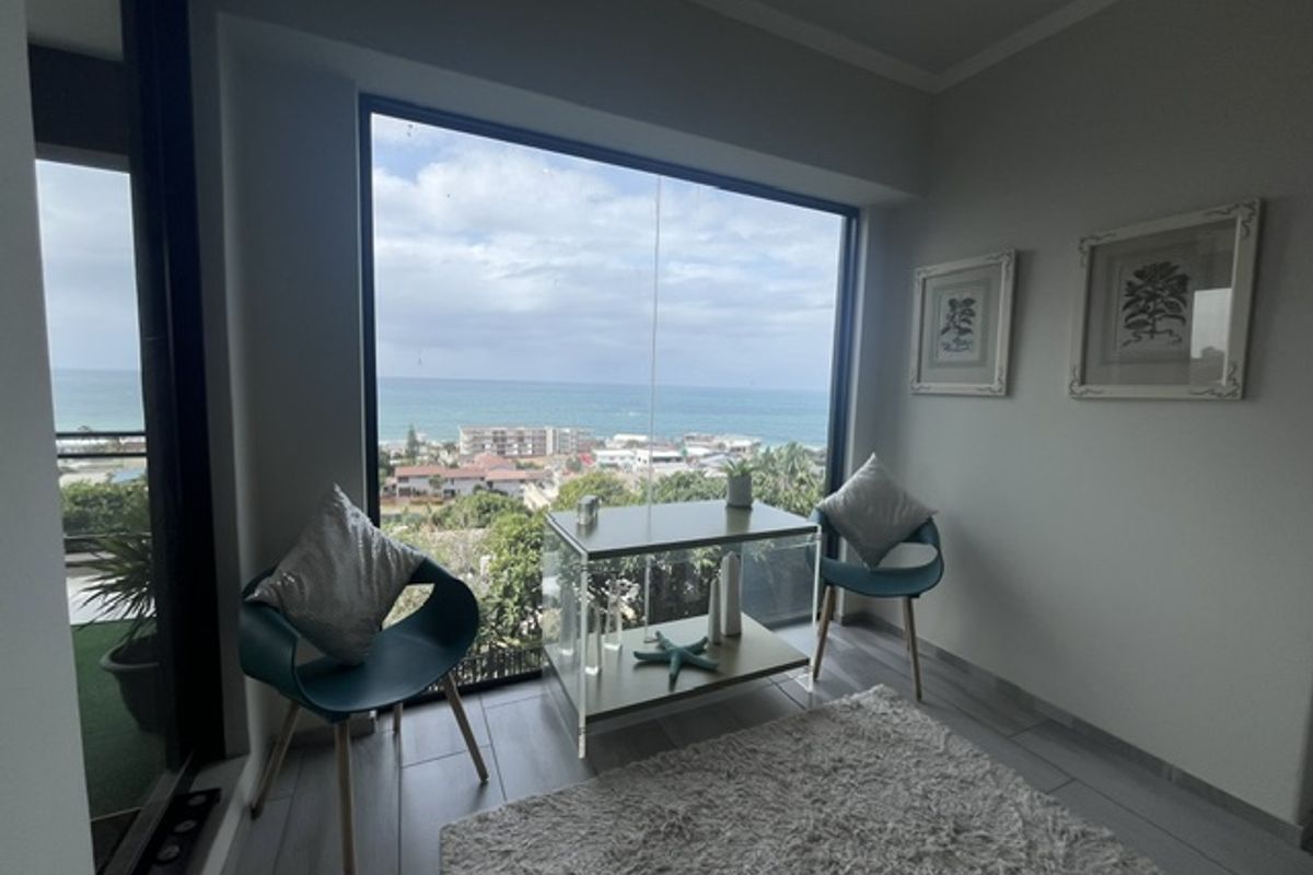 A bright living area featuring a large picture window with expansive ocean views and direct access to an adjacent balcony.