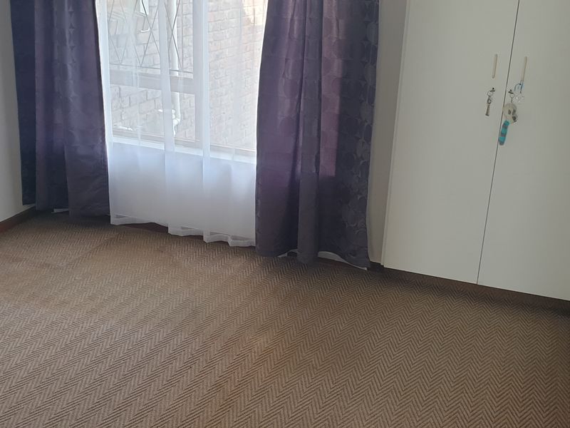 A simple bedroom featuring built-in wardrobes and carpeted flooring, offering a clean and functional space ready for personalization.