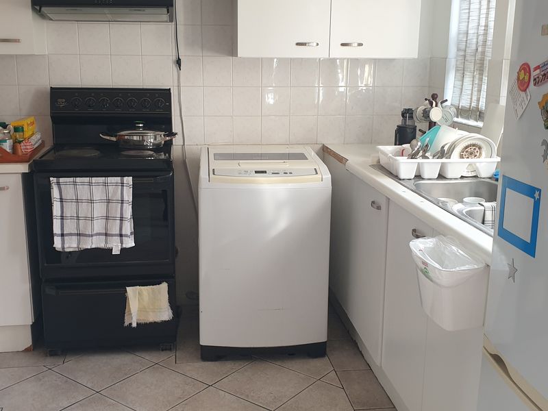A functional kitchen featuring white cabinetry, tiled backsplash, and integrated appliances, offering a practical layout for daily meal preparation.