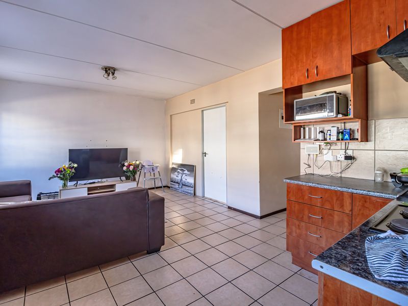 Open-plan living area featuring a functional kitchen with built-in cabinetry, laminate countertops, and tiled flooring throughout the combined space.
