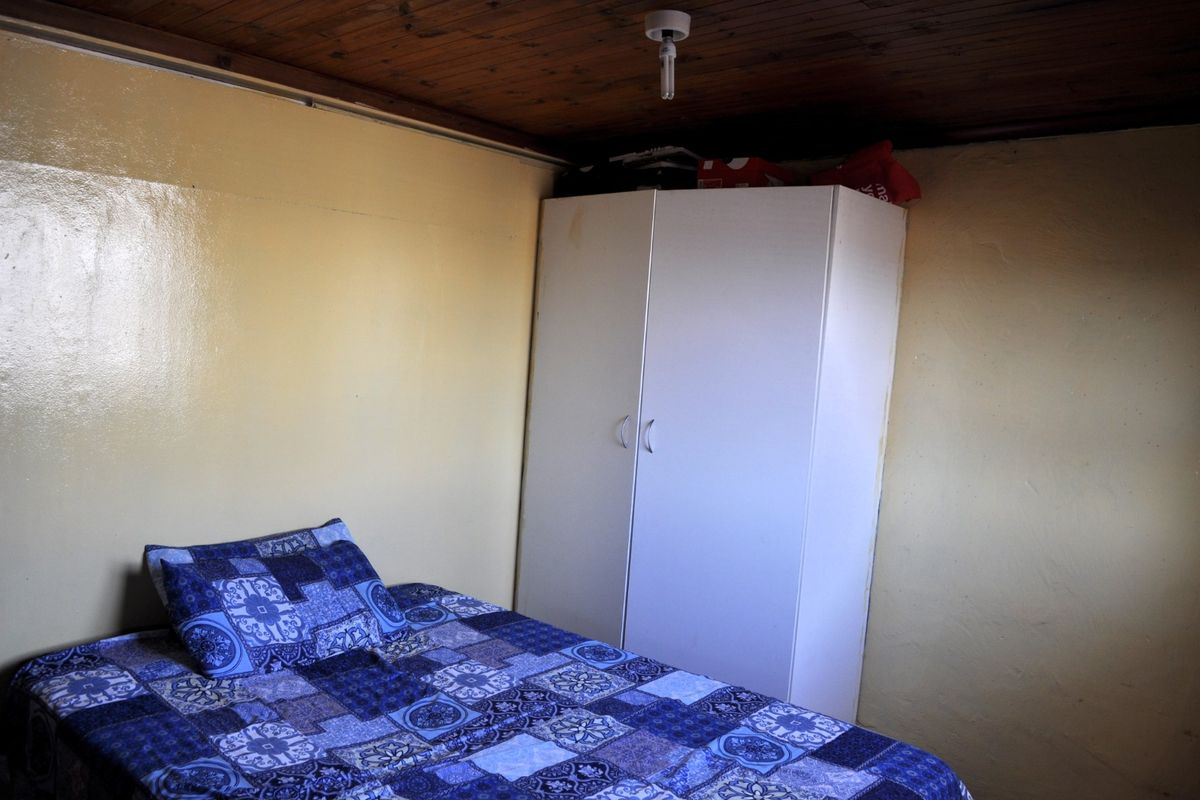 A compact bedroom featuring a timber-paneled ceiling and painted walls, providing a basic sleeping space.