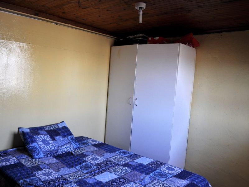 A compact bedroom featuring a timber-paneled ceiling and painted walls, providing a basic sleeping space.