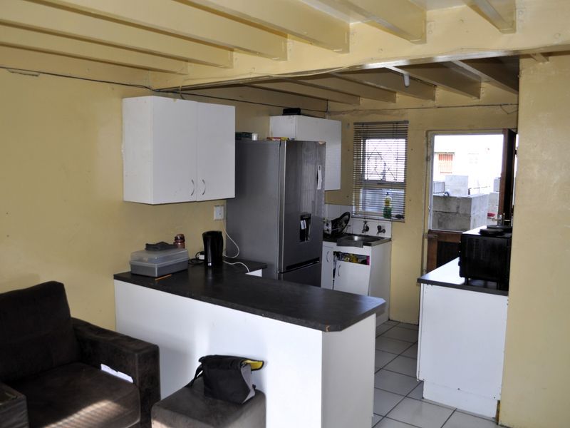 A functional kitchen featuring white cabinetry, dark countertops, and exposed ceiling beams, offering a practical layout with direct access to the exterior.