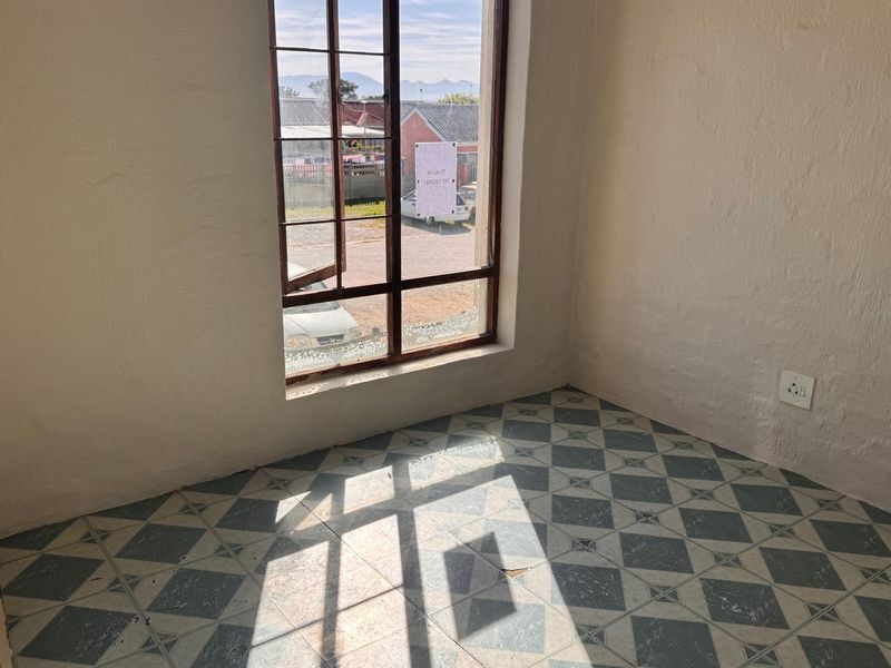 An empty bedroom featuring patterned ceramic floor tiles and a timber-framed window with natural light.