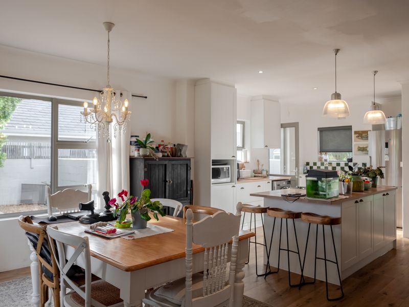 Spacious open-plan kitchen and dining area featuring a central island, modern cabinetry, timber flooring, and elegant pendant lighting, creating a bright and functional living space.