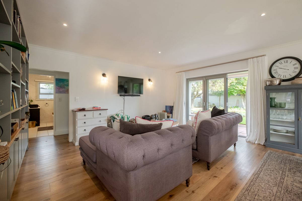 A bright living room featuring timber flooring, built-in shelving, and sliding glass doors that provide direct access to the rear garden.