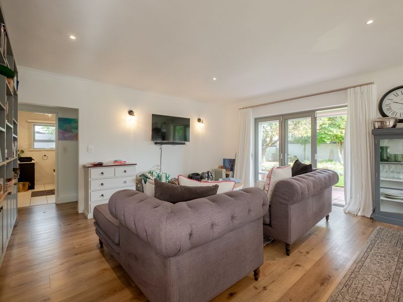 A bright living room featuring timber flooring, built-in shelving, and sliding glass doors that provide direct access to the rear garden.
