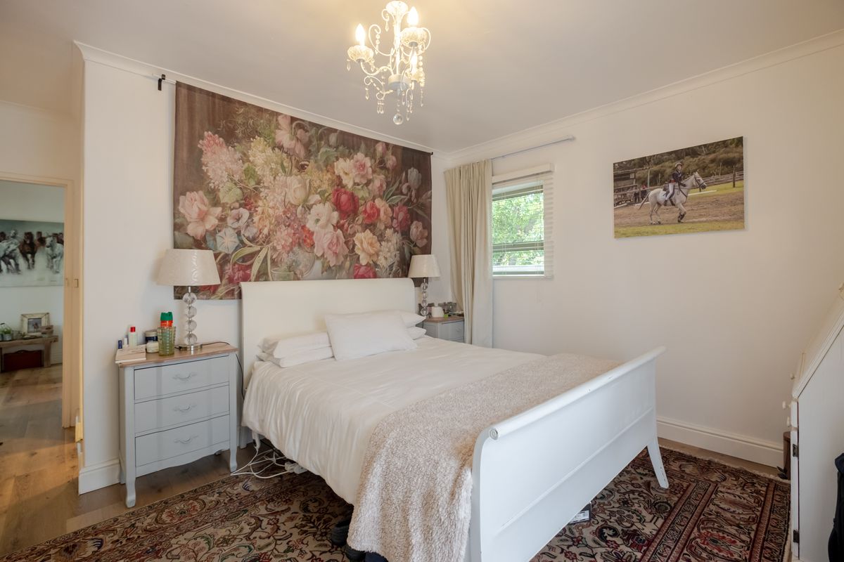 A well-maintained bedroom featuring classic coving, neutral walls, and a central chandelier, offering a comfortable and inviting living space.
