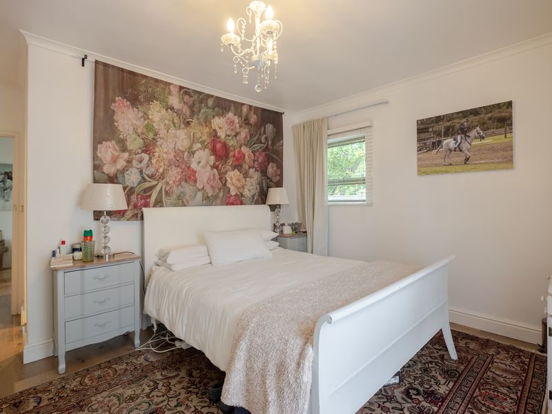 A well-maintained bedroom featuring classic coving, neutral walls, and a central chandelier, offering a comfortable and inviting living space.