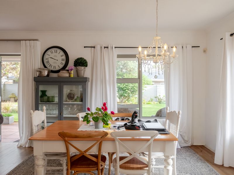 Bright dining area featuring laminate flooring, a decorative chandelier, and large sliding glass doors providing direct access to the rear garden.