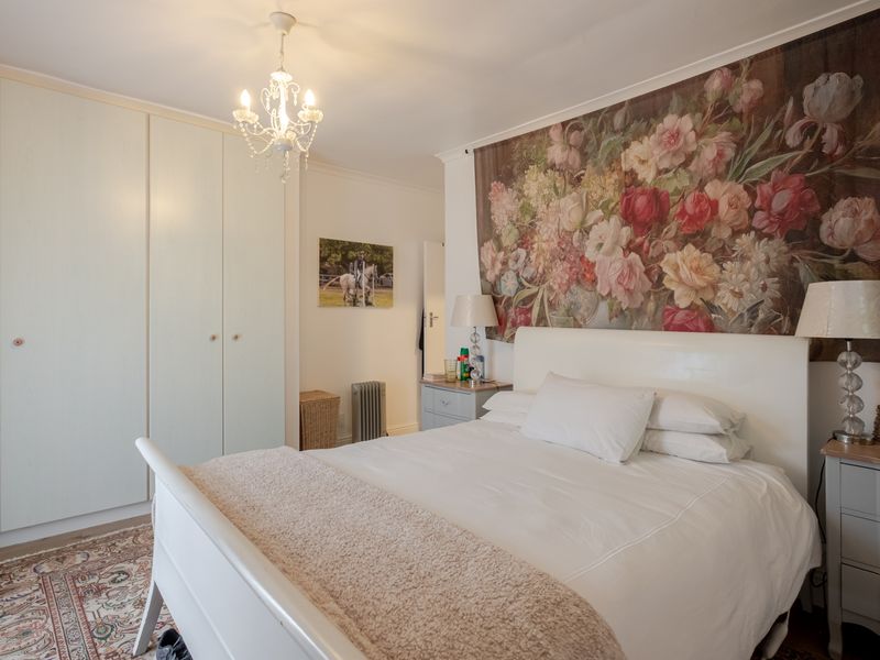 A bedroom featuring built-in wardrobes and a central ceiling light fixture, offering a functional space with neutral finishes.