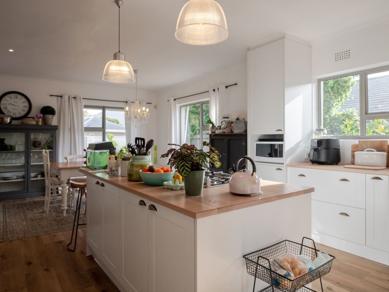 A bright open-plan kitchen featuring a central island with wooden countertops, modern cabinetry, and integrated appliances, seamlessly flowing into the dining area.