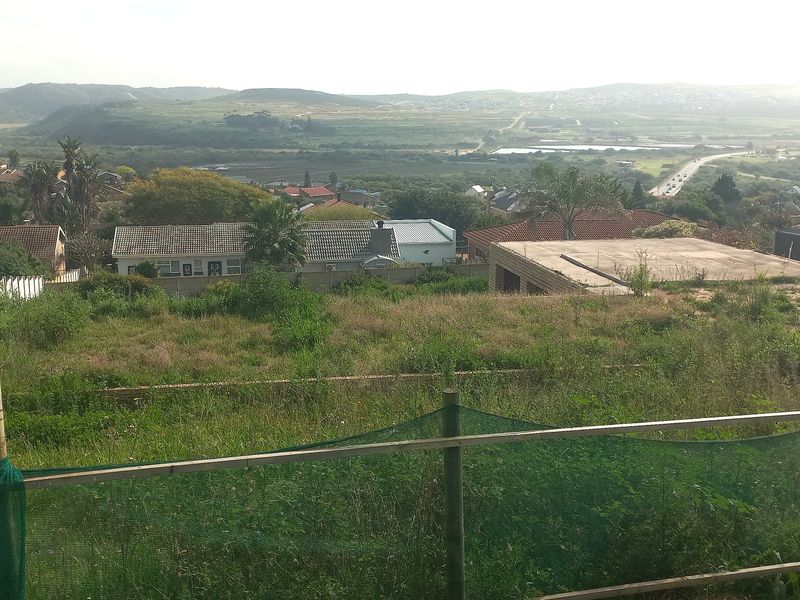 Elevated view overlooking a residential neighborhood and surrounding landscape from a vacant plot of land.