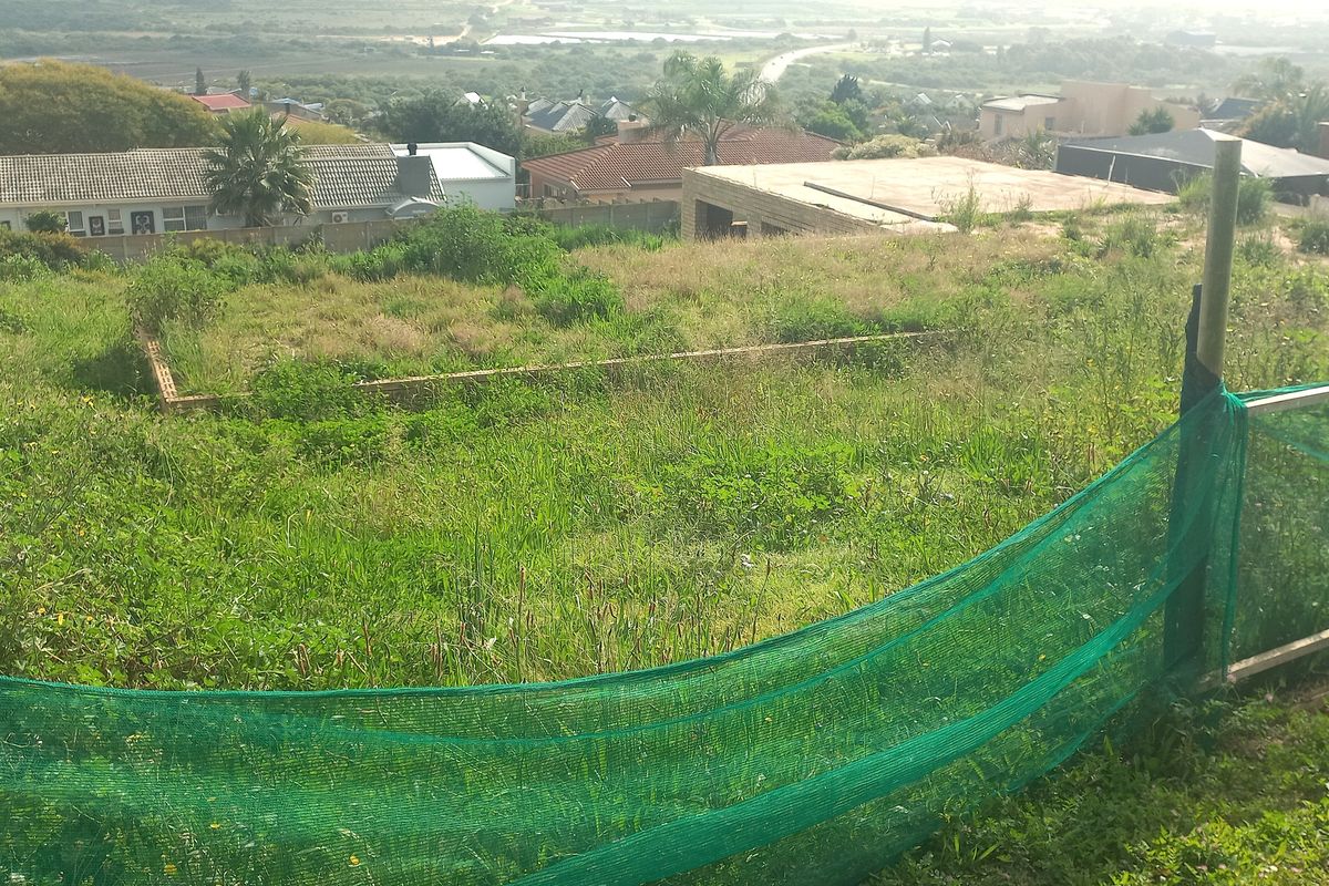 A vacant residential plot featuring perimeter fencing and a partial foundation, situated in a developed neighborhood with surrounding residential properties.