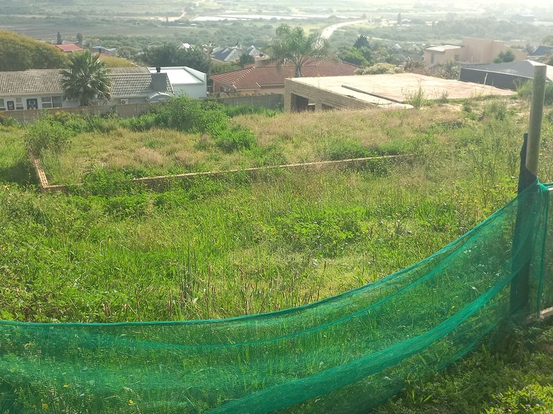 A vacant residential plot featuring perimeter fencing and a partial foundation, situated in a developed neighborhood with surrounding residential properties.