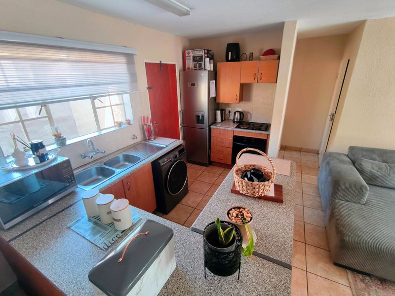 Open plan kitchen featuring granite countertops, built-in oven, hob, and double sink, seamlessly flowing into the adjacent living area.