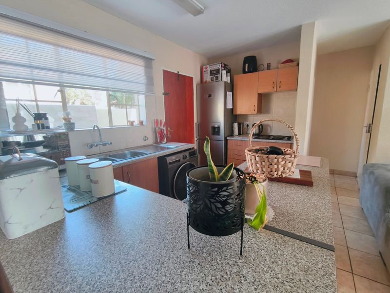 A functional kitchen featuring laminate countertops, built-in cabinetry, and a double basin stainless steel sink with tiled flooring.