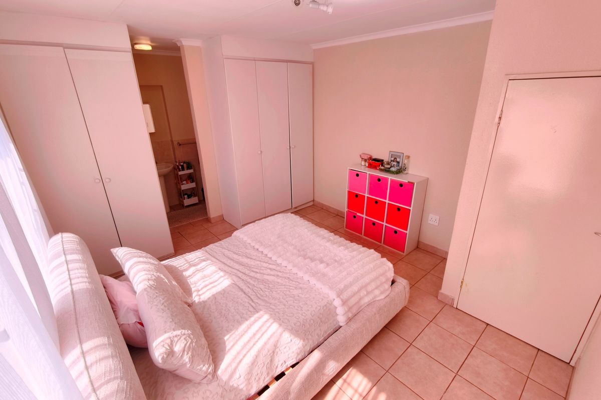 A bedroom featuring built-in cupboards, tiled flooring, and direct access to an en-suite bathroom.