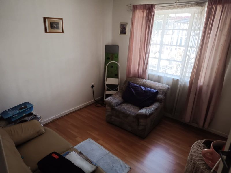 A bedroom featuring laminate flooring and a window fitted with security bars, offering a functional space with potential for cosmetic updates.