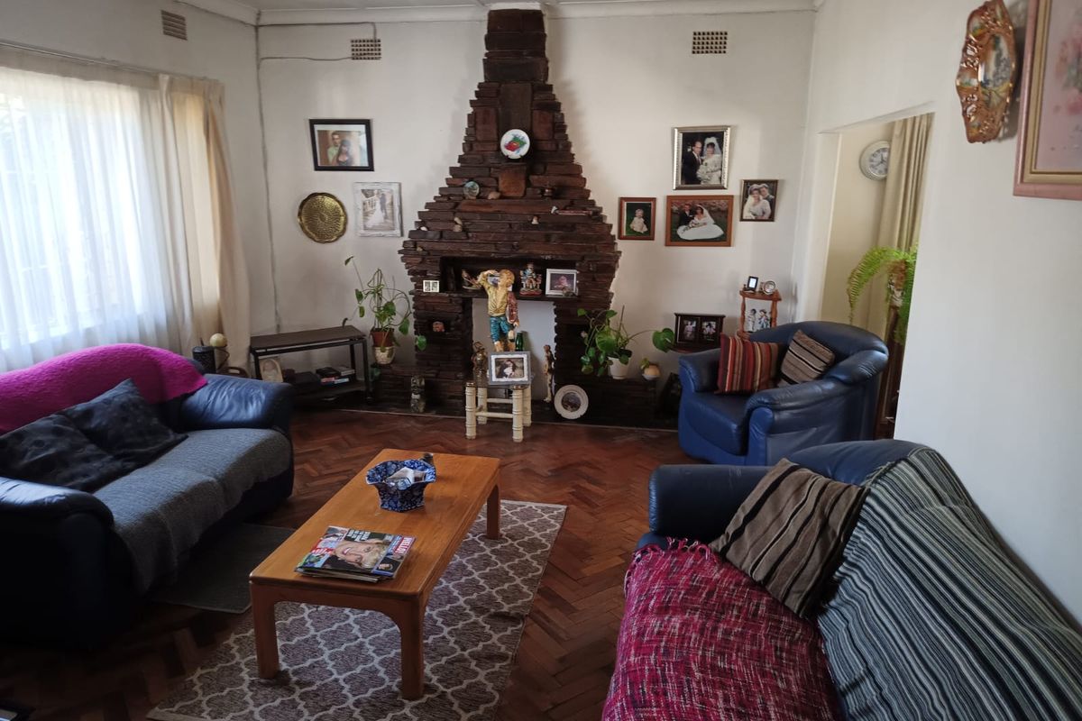 A living room featuring a prominent brick fireplace and traditional parquet flooring, offering a classic foundation for modern interior updates.