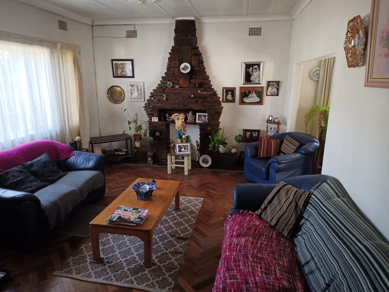 A living room featuring a prominent brick fireplace and traditional parquet flooring, offering a classic foundation for modern interior updates.