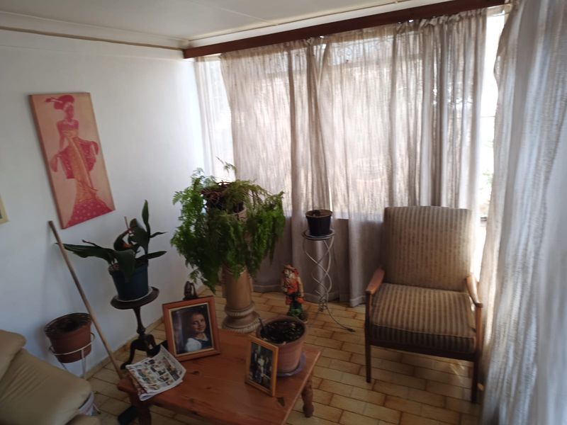 A sun-filled enclosed patio or sunroom featuring tiled flooring and large windows with curtain treatments, offering a bright and versatile living space.