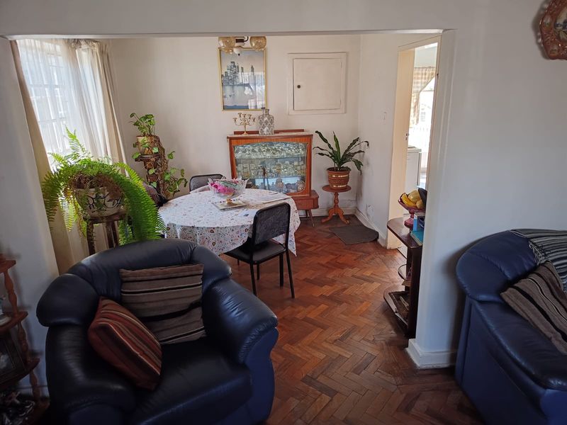 Open plan living and dining area featuring classic herringbone parquet flooring and neutral wall finishes, offering a versatile space for family living.