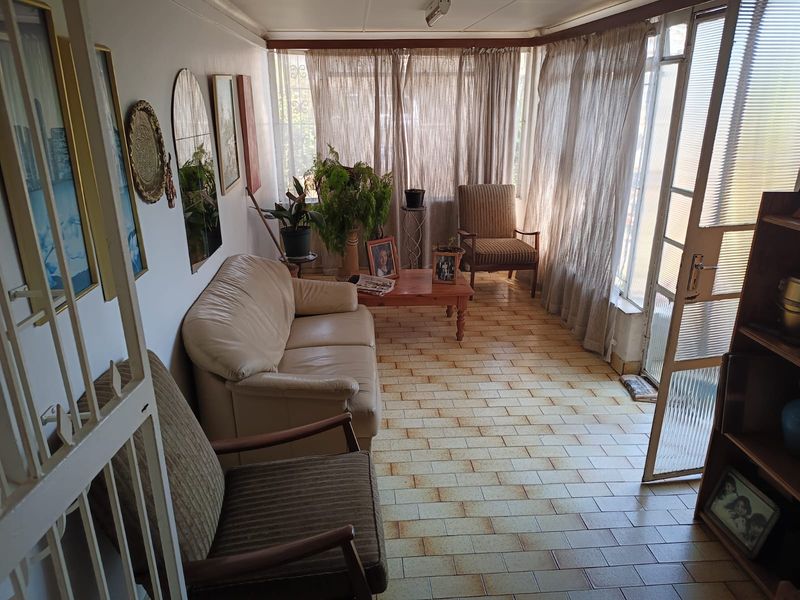 A sunroom or enclosed patio area featuring tiled flooring, large windows with curtains, and direct access to the exterior via a sliding glass door.