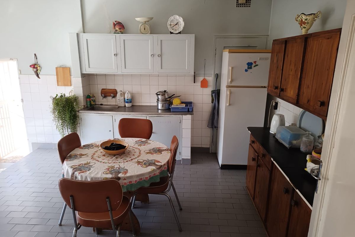 A dated kitchen featuring original cabinetry, tiled splashbacks, and tiled flooring, offering significant potential for a modern renovation.