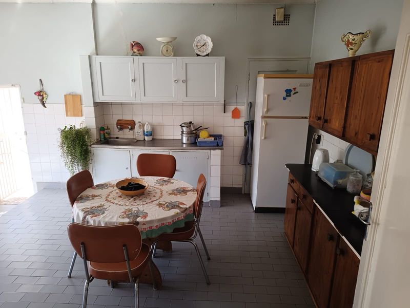 A dated kitchen featuring original cabinetry, tiled splashbacks, and tiled flooring, offering significant potential for a modern renovation.