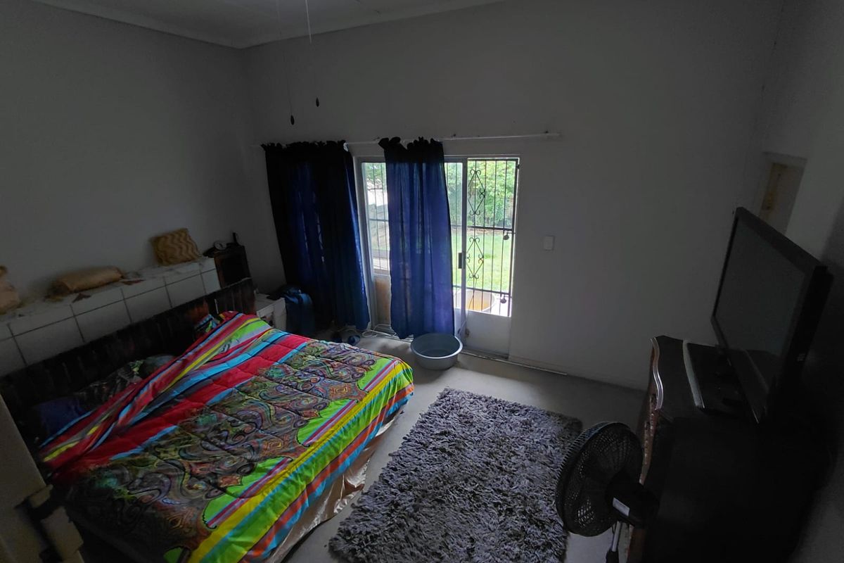 A bedroom featuring a ceiling fan and a sliding glass door with a security gate, providing direct access to the outdoor area.