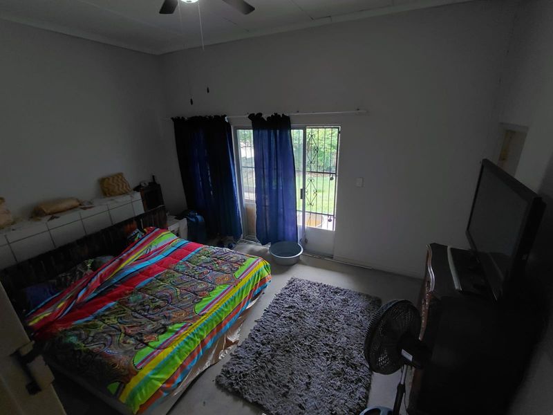 A bedroom featuring a ceiling fan and a sliding glass door with a security gate, providing direct access to the outdoor area.