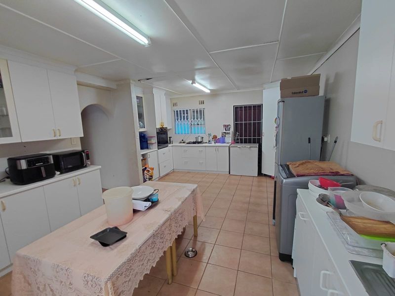 A functional kitchen featuring tiled flooring, built-in cabinetry, and security fixtures, offering a practical layout with potential for modern updates.