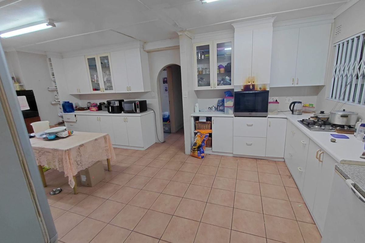 Spacious kitchen featuring white built-in cabinetry, gas hob, and tiled flooring. The space offers ample storage and potential for modernization.