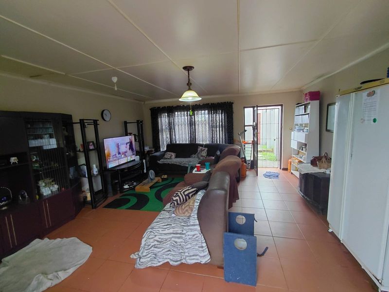 A living room featuring tiled flooring, ceiling panels, and direct access to the exterior through a security gate.