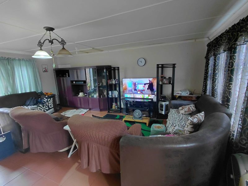 A living room featuring tiled flooring and ceiling panels, offering a functional space that could benefit from modern updates to enhance its overall appeal.