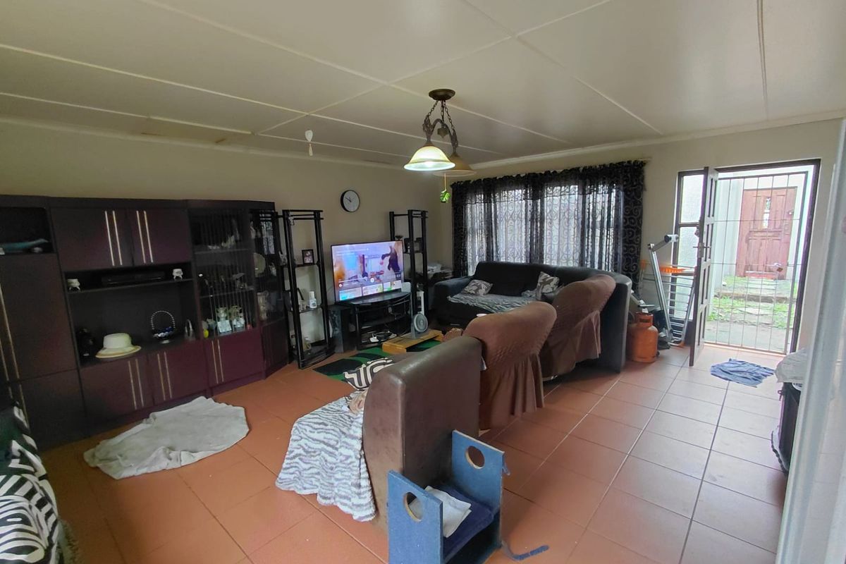 A living room featuring tiled flooring, a ceiling light fixture, and direct access to the exterior via a security gate.