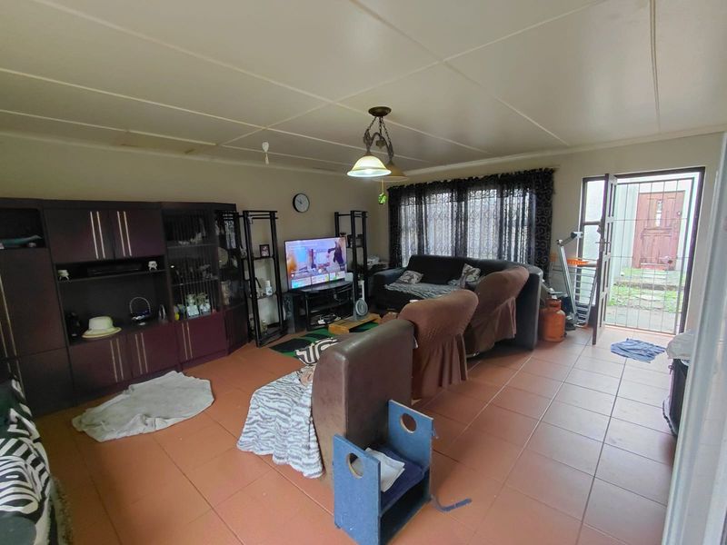 A living room featuring tiled flooring, a ceiling light fixture, and direct access to the exterior via a security gate.