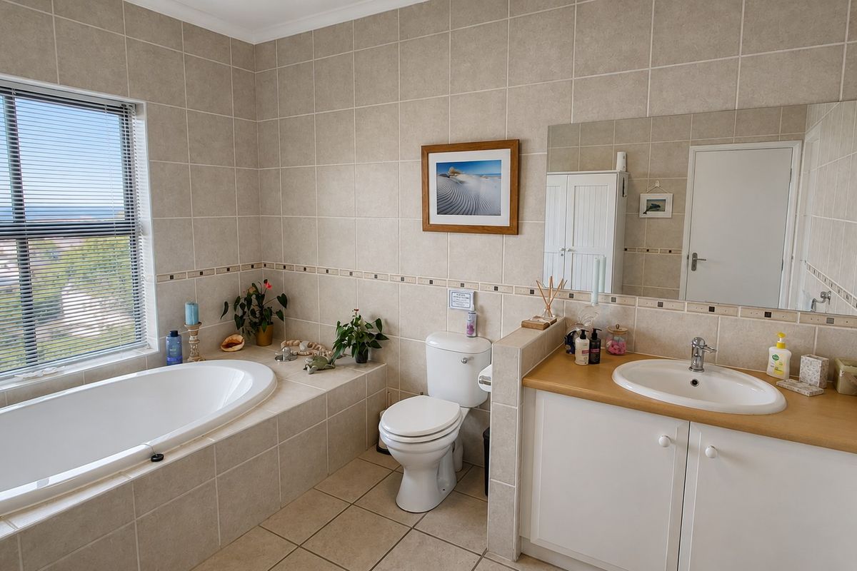 A functional bathroom featuring a built-in bathtub, vanity cabinet with integrated basin, toilet, and neutral ceramic tiling throughout.