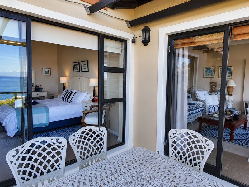A spacious covered balcony featuring tiled flooring, sliding glass doors providing access to interior rooms, and scenic ocean views.