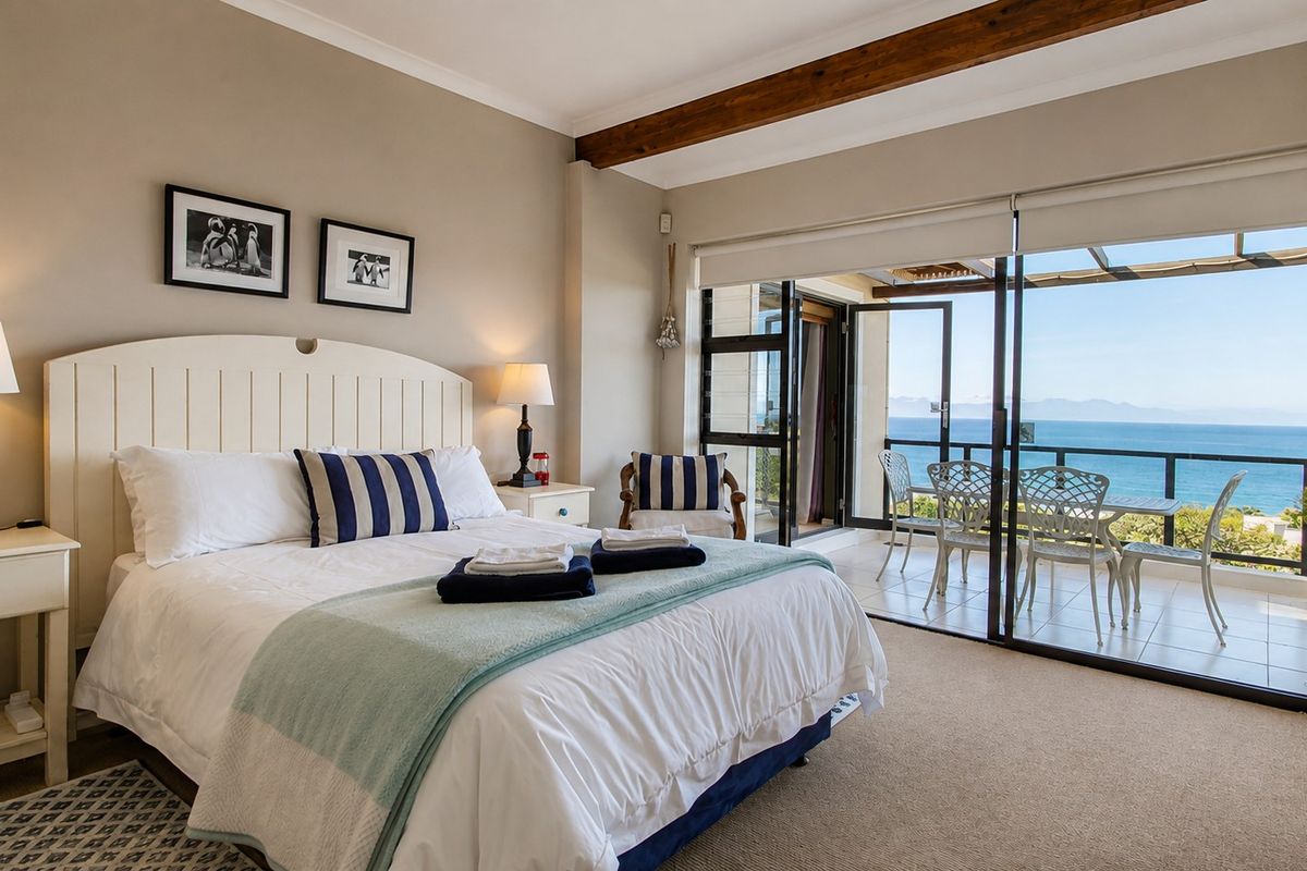 Spacious bedroom featuring exposed timber ceiling beams, neutral carpeting, and large sliding glass doors opening onto a private balcony with ocean views.