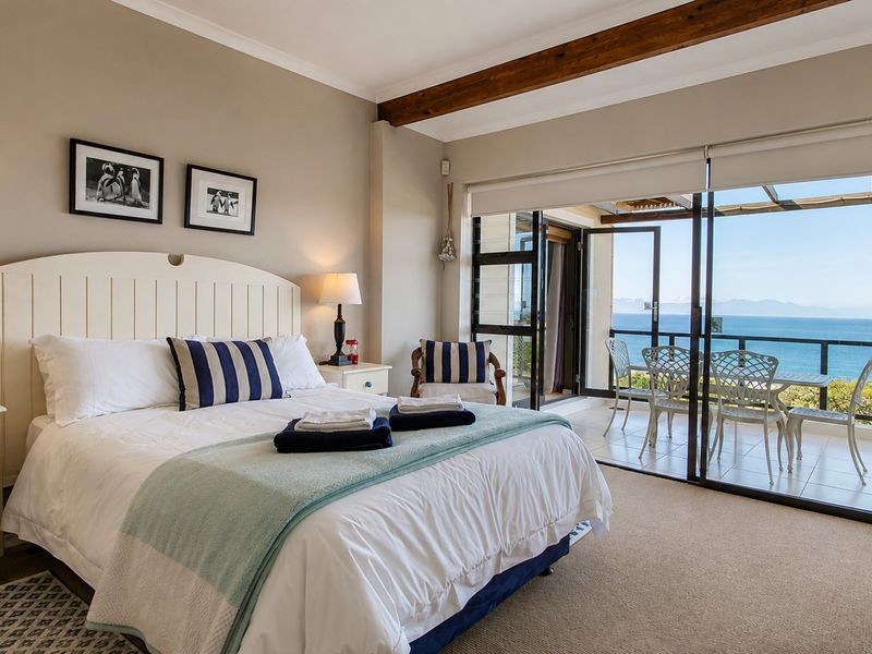 Spacious bedroom featuring exposed timber ceiling beams, neutral carpeting, and large sliding glass doors opening onto a private balcony with ocean views.