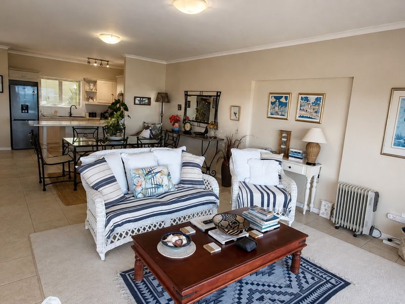 An open-plan living and kitchen area featuring tiled floors, neutral wall tones, and a functional kitchen layout with a central island.