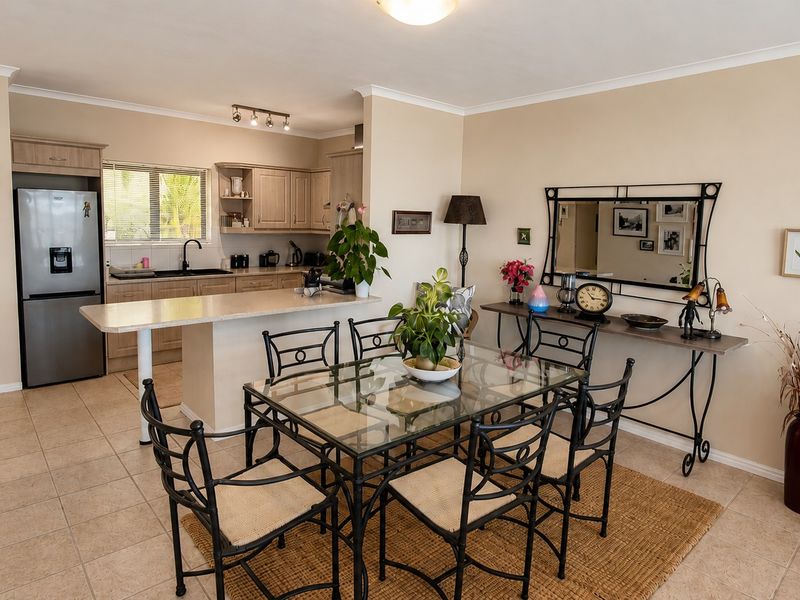 Open-plan kitchen and dining area featuring tiled flooring, neutral cabinetry, and a breakfast bar island, creating a functional and connected living space.