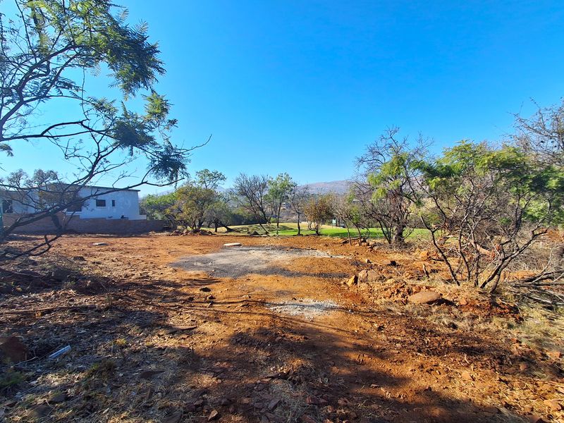 A view of a vacant residential plot featuring cleared ground and established trees, offering a blank canvas for future development.