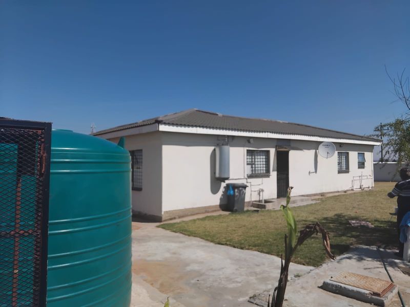 Rear view of the house featuring a water storage tank, external geyser, and security bars on the windows.
