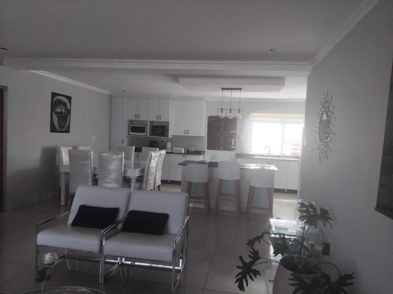 Open-plan living and kitchen area featuring tiled floors, modern white cabinetry, a central kitchen island, and recessed lighting.