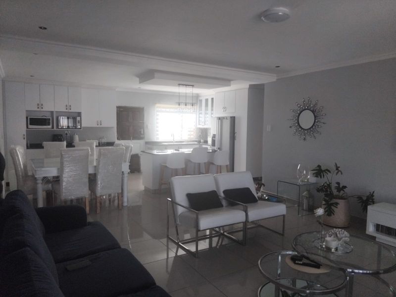 Spacious open-plan living and dining area featuring a modern kitchen with built-in cabinetry, a central island, and polished tiled flooring throughout.