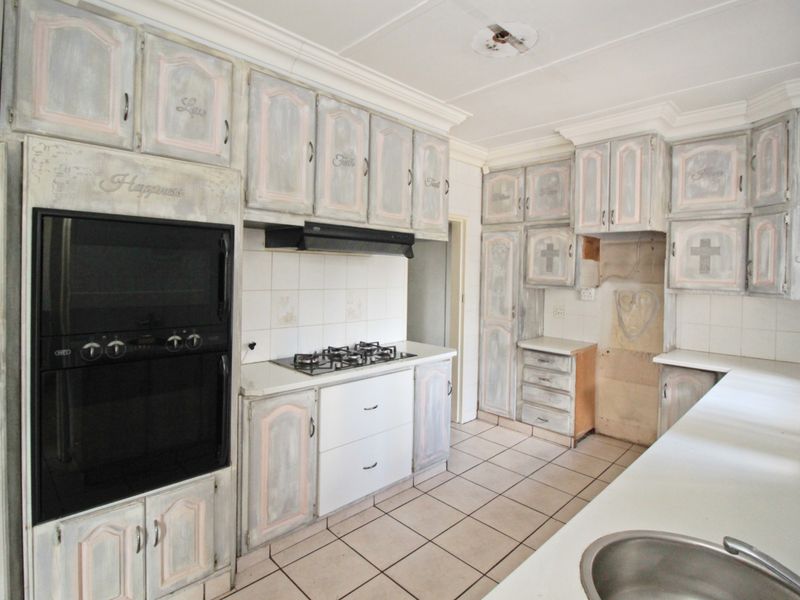 A dated kitchen featuring built-in cabinetry, a gas hob, and an integrated oven, offering a functional layout ready for modern renovation and cosmetic updates.