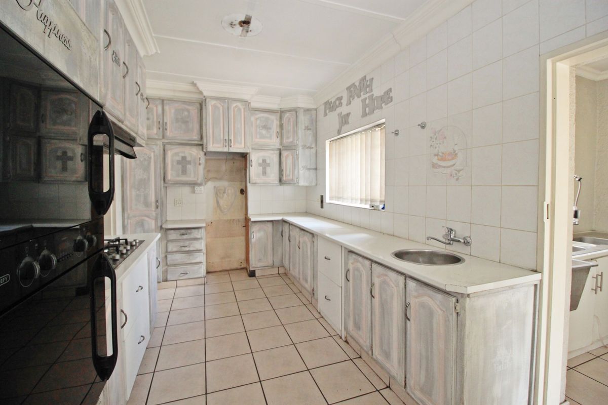 A functional kitchen featuring tiled flooring, built-in cabinetry, a gas hob, and an integrated oven, offering a blank canvas for modern renovation.